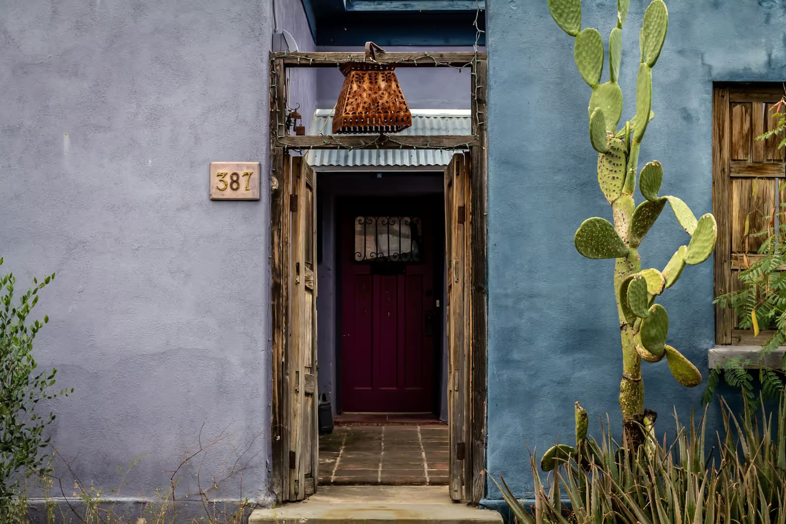 Entrance of a Mexican house with wooden doors and a prickly pear cactus