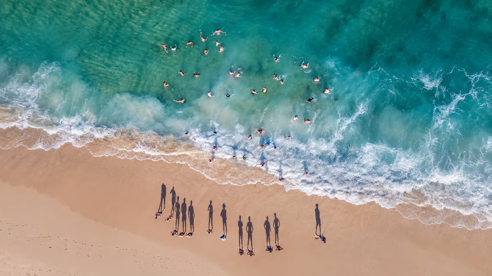 Vista aérea de bañistas en aguas turquesa junto a la orilla