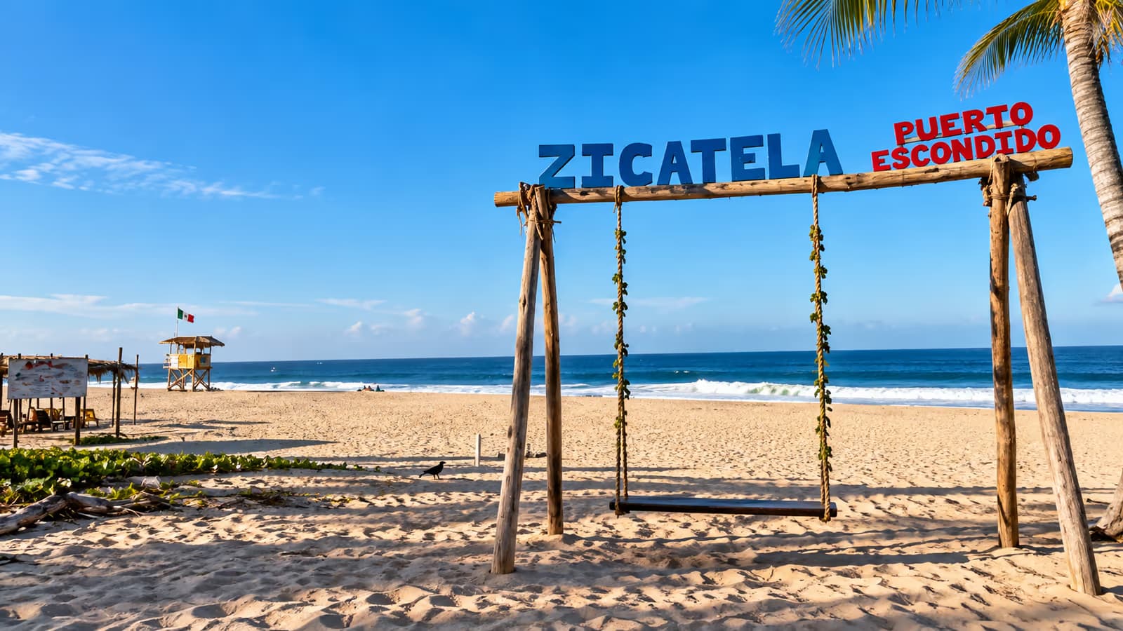 Wooden swing with the Zicatela Puerto Escondido sign on the sand, with the sea in the background