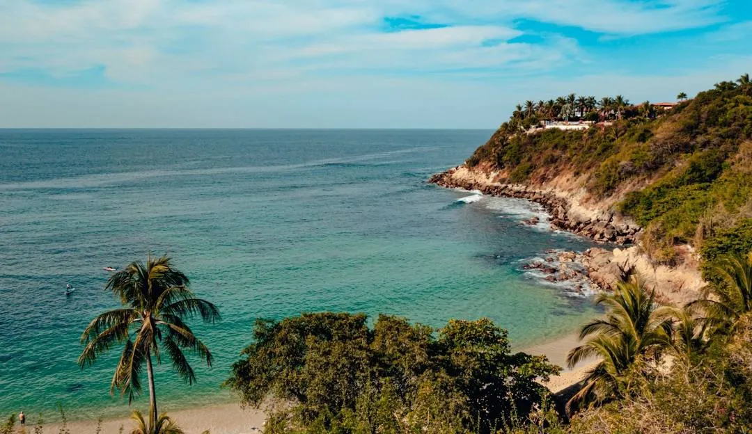 Sandy cove with palm trees and clifftop houses in Puerto Escondido