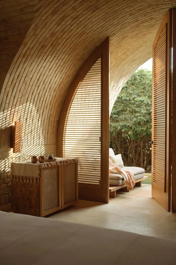 Brick vaulted interior with a wooden lattice opening onto greenery