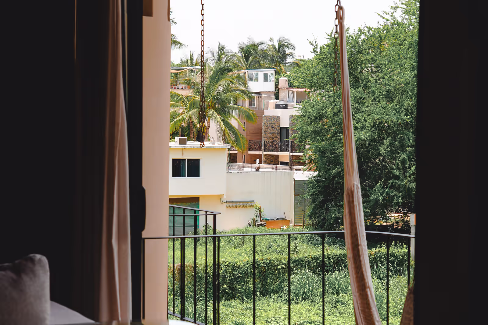 Apartment balcony in Puerto Escondido with a hammock and a view of palm trees