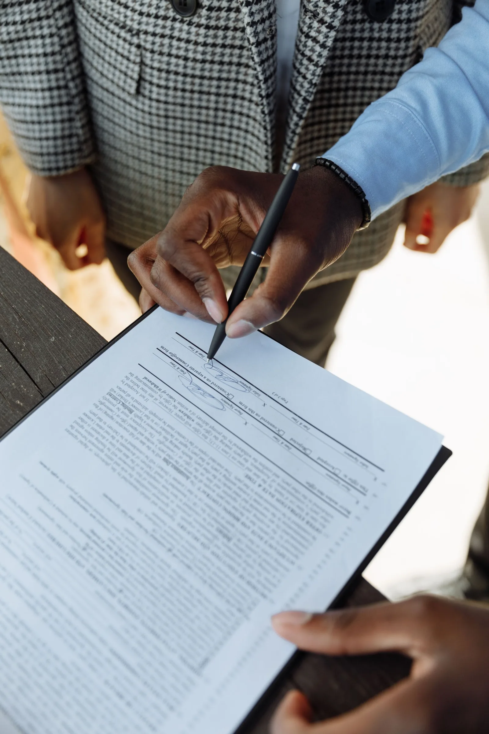 Hands signing a document with a pen on a folder
