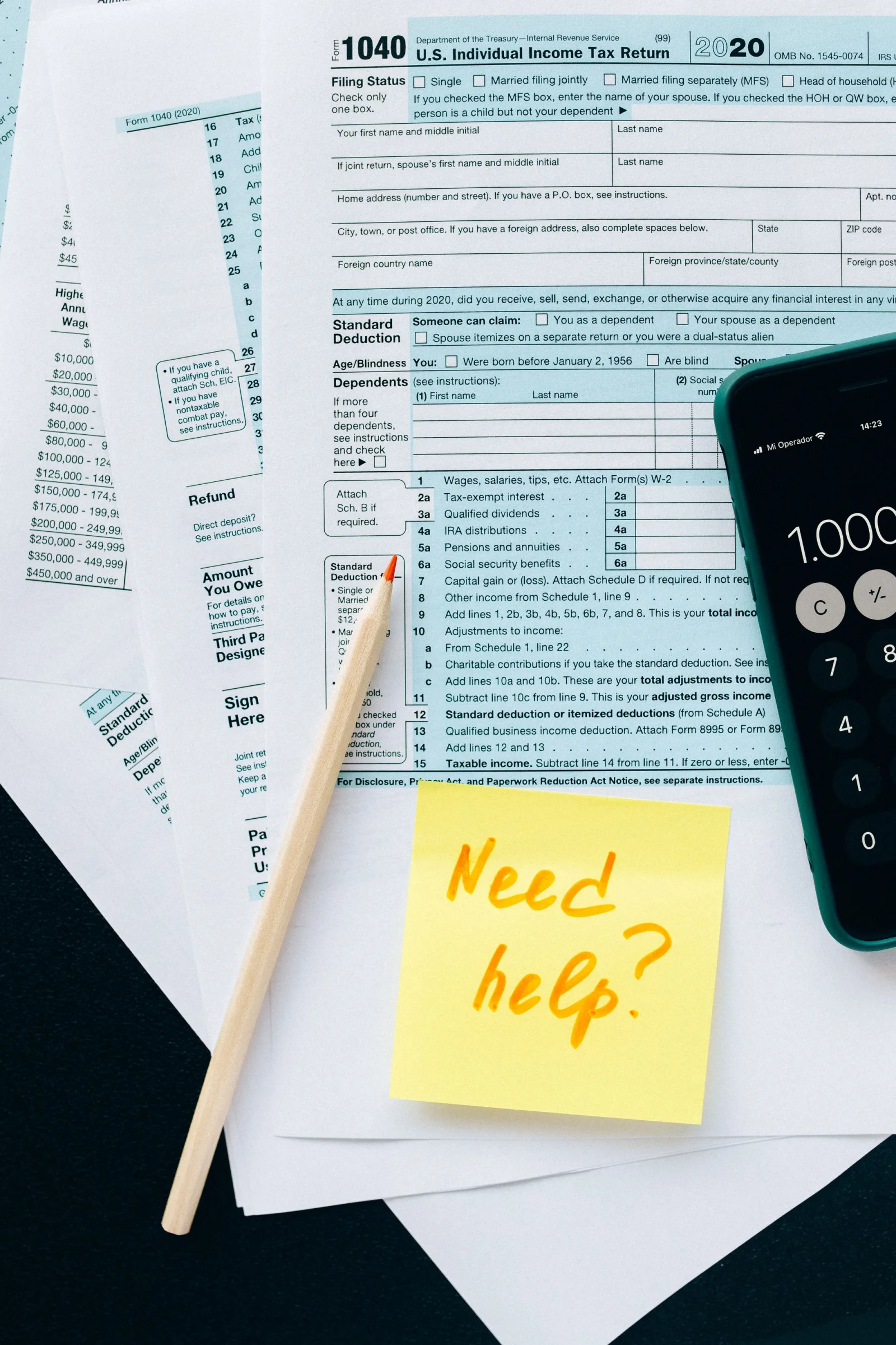 Tax forms with a calculator, a pencil and a sticky note